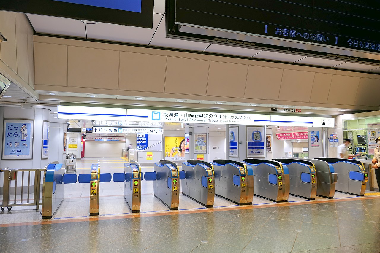 Tokyo Station transfer gates with travelers moving through layered rail signage.